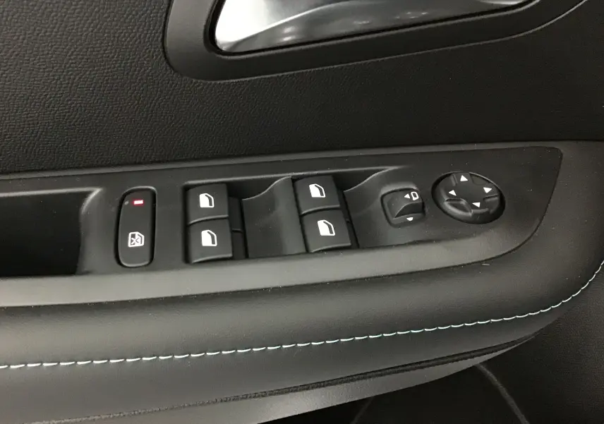Gros plan sur la commande des vitres et des rétroviseurs côté conducteur d'une Peugeot 208 blanche 2024.