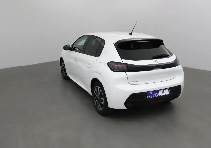 Peugeot 208 blanc vue 3/4 arrière droit, feux arrière sombres et jantes alliage 16 pouces visibles.