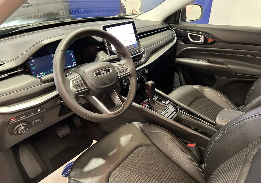 Intérieur du Jeep Compass Limited 2021, vue côté conducteur montrant tableau de bord numérique et sellerie cuir noire.