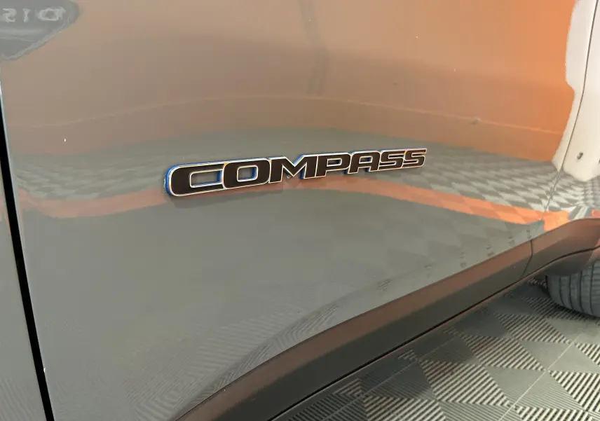 Gros plan sur l’inscription Compass sur la porte côté gauche d’un Jeep Compass gris métallisé.