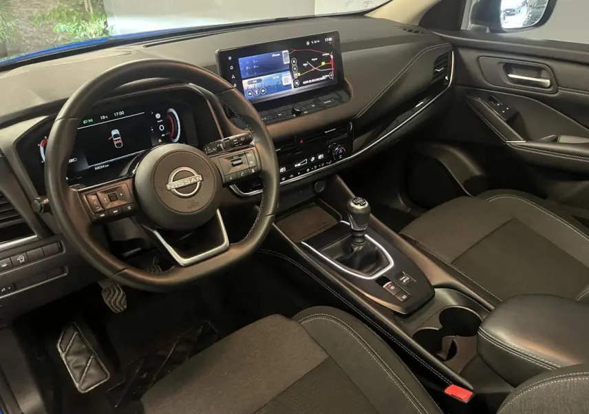 Intérieur avant du Nissan Qashqai 1.3 Mild Hybrid 2024, volant cuir, écran tactile 12,3 pouces et boîte manuelle visible.