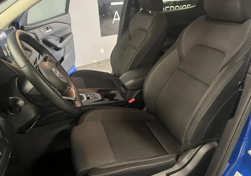 Vue intérieure côté conducteur du Nissan Qashqai 1.3 Mild Hybrid 140 Shadow bleu, sièges tissu noir et console centrale.