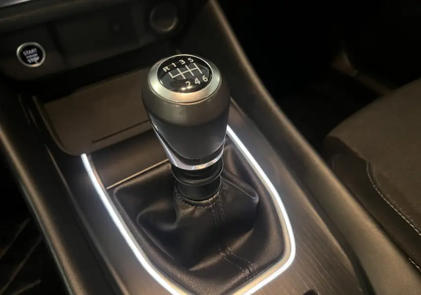 Le levier de vitesses manuel noir du Nissan Qashqai 1.3 Mild Hybrid 140 Shadow vu en gros plan sur la console centrale.