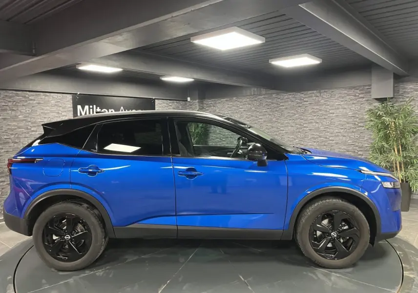 Vue de profil côté gauche d'un Nissan Qashqai 1.3 Mild Hybrid 140 Shadow bleu avec toit noir et jantes noires.
