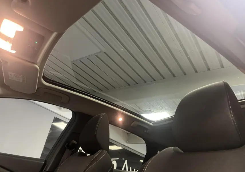 Vue intérieure du toit panoramique en verre et des sièges avant en tissu gris du Nissan Qashqai 2024.