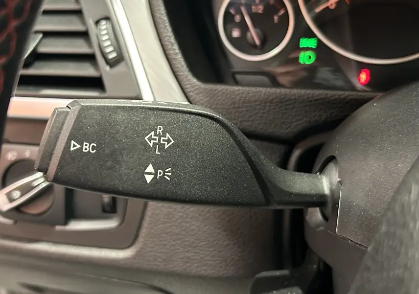 Gros plan sur la commande de clignotant à gauche du volant dans l'habitacle d'une BMW Série 3 blanche 320i 2018.