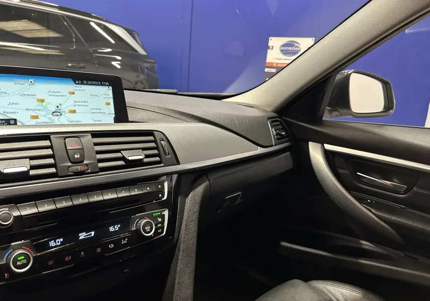 Vue intérieure côté passager de la BMW Série 3 320i blanche de 2018, avec tableau de bord et écran GPS visibles.