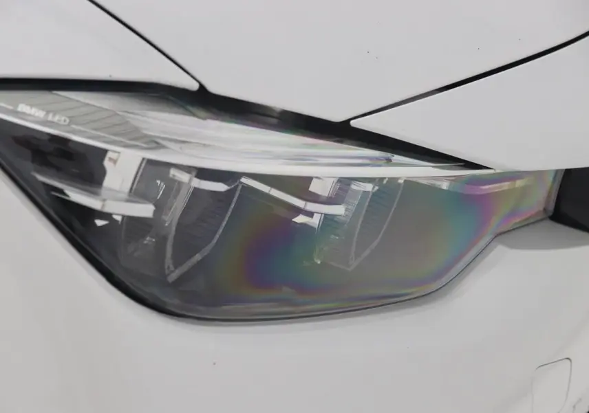 Gros plan sur le phare avant gauche LED d'une BMW Série 3 320i blanche de 2018 avec carrosserie lisse.