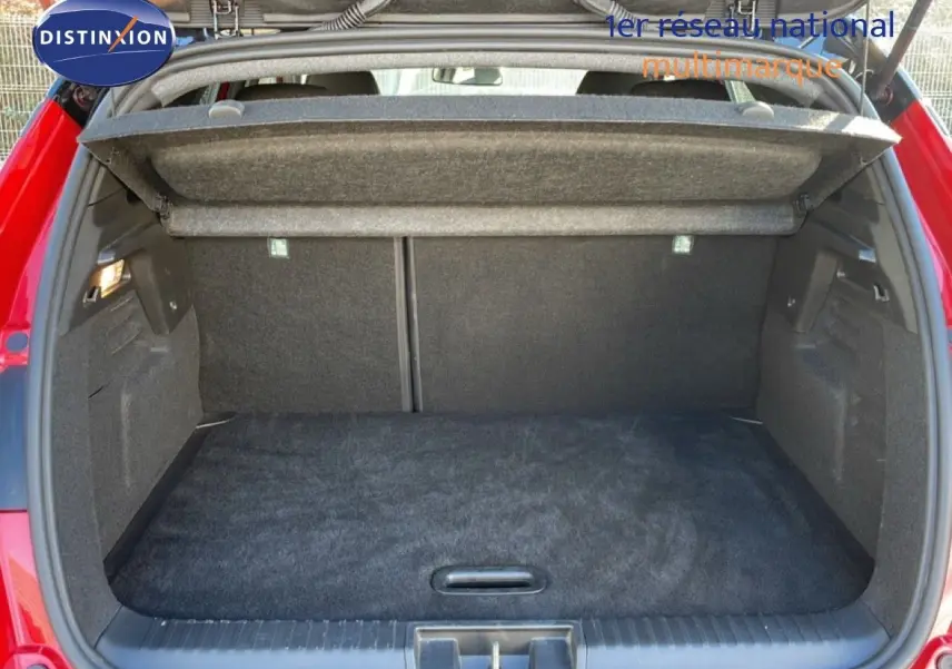 Coffre ouvert vu de l'arrière d'un Renault Captur 2025 rouge Désir métal avec toit noir, intérieur de coffre noir.