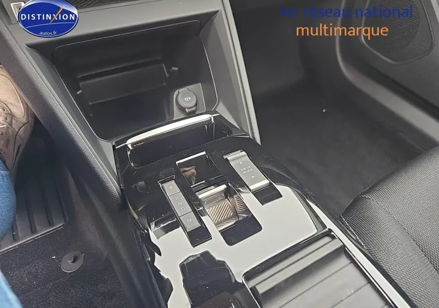 Gros plan sur la console centrale brillante de la Citroën C4 noire hybride, avec levier de vitesses automatique et bouton Drive Mode.