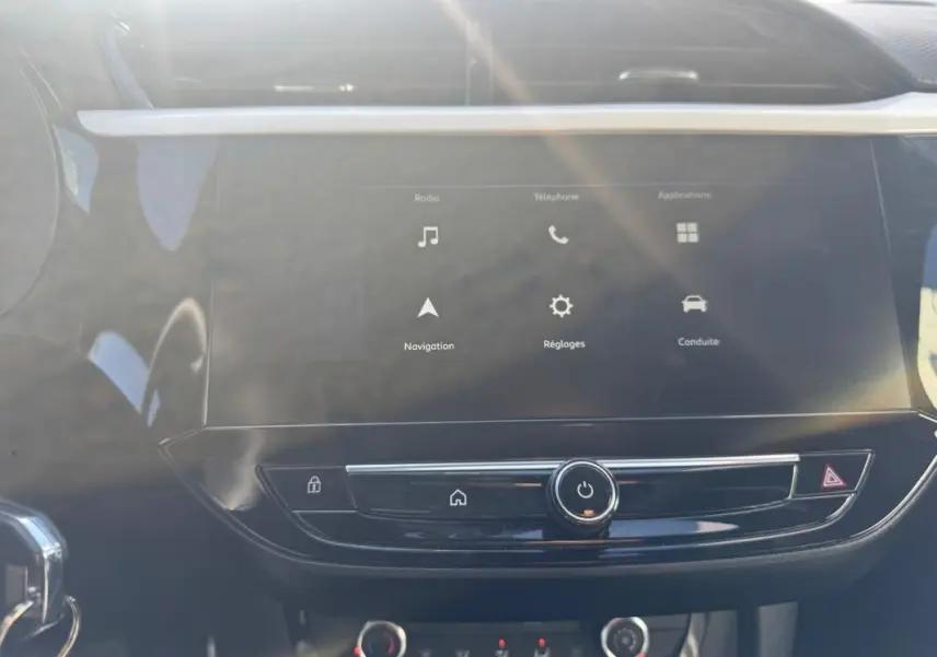 Vue rapprochée de l’écran tactile central de l’Opel Corsa rouge 2025, affichant les menus radio, navigation et réglages.