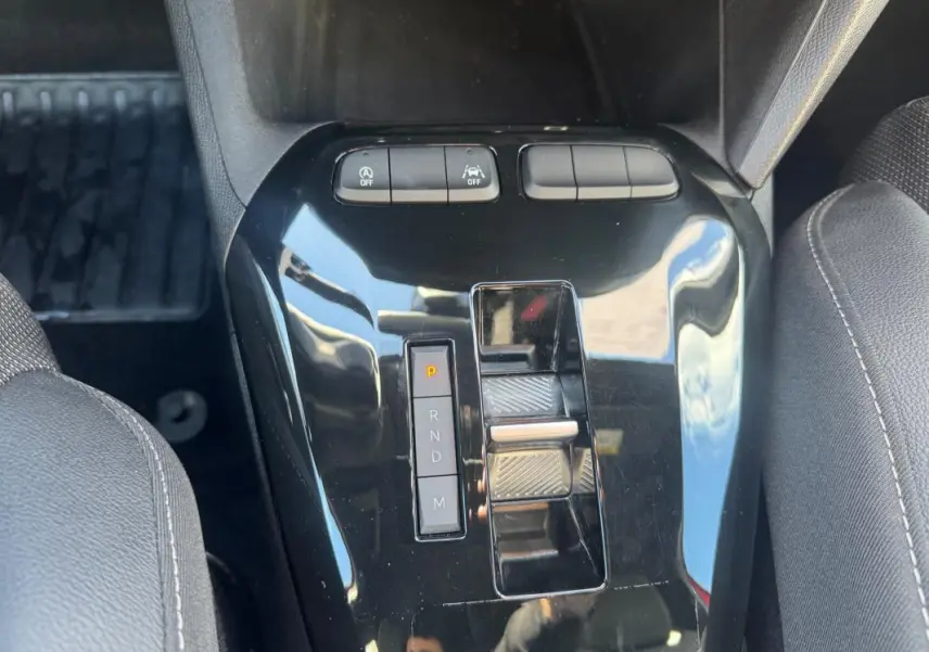 Vue rapprochée de la console centrale noire avec levier de boîte automatique et boutons de contrôle dans une Opel Corsa rouge.