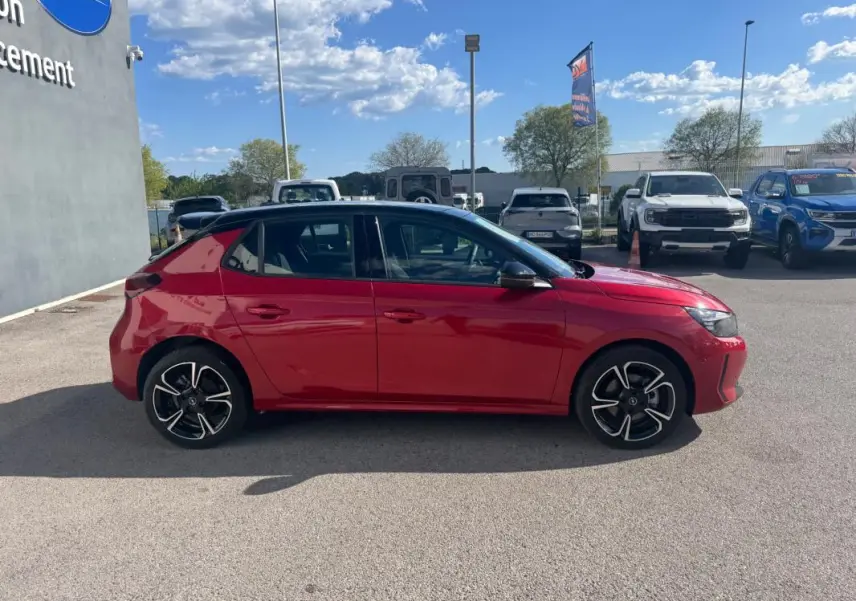 Vue de profil côté gauche d'une Opel Corsa rouge 2025 avec jantes alliage noires et toit noir.