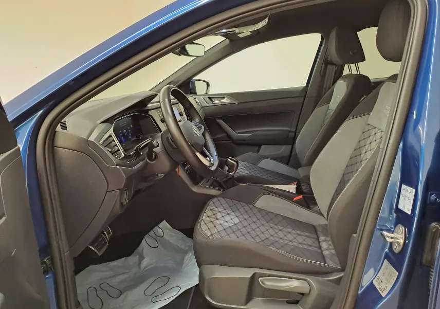 Vue intérieure côté conducteur de la Volkswagen Polo Bleu Récif, montrant les sièges R-Line et le tableau de bord moderne.