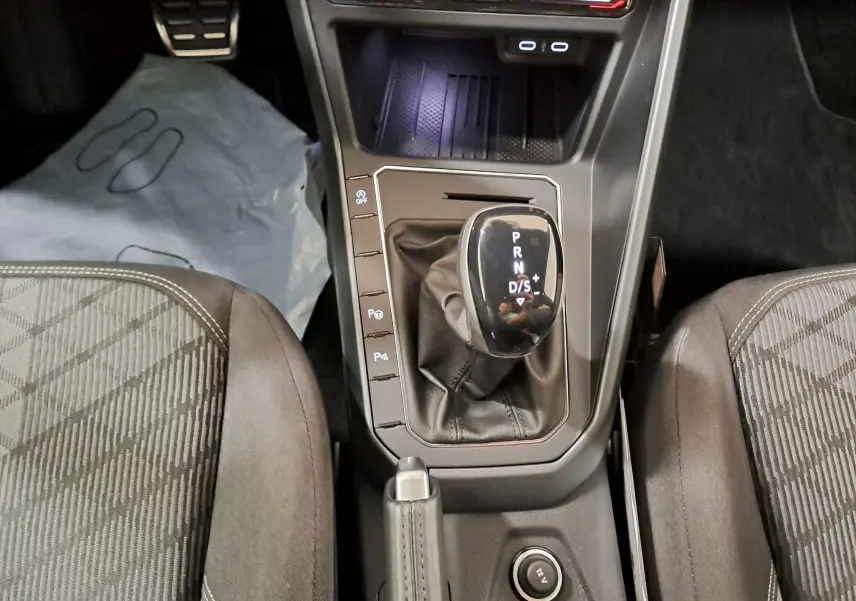 Vue plongeante sur la console centrale de la Volkswagen Polo 2025, avec levier de vitesse automatique et sièges tissu gris.