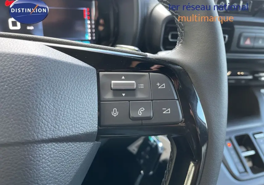Gros plan sur les commandes au volant du Citroën Berlingo noir Perla Nera, avec tableau de bord numérique en arrière-plan.