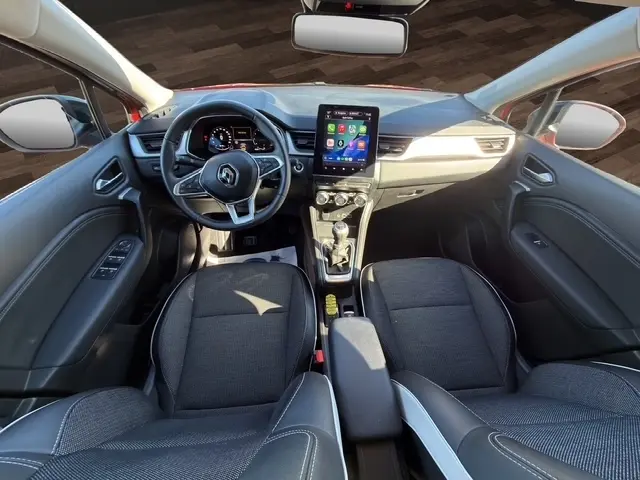 Vue intérieure avant du Renault Captur rouge 2024, avec tableau de bord numérique et écran tactile central vertical.