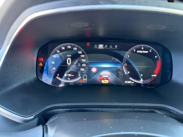 Tableau de bord numérique du Renault Captur 2024 affichant vitesse, compte-tours et alertes, vue frontale rapprochée.