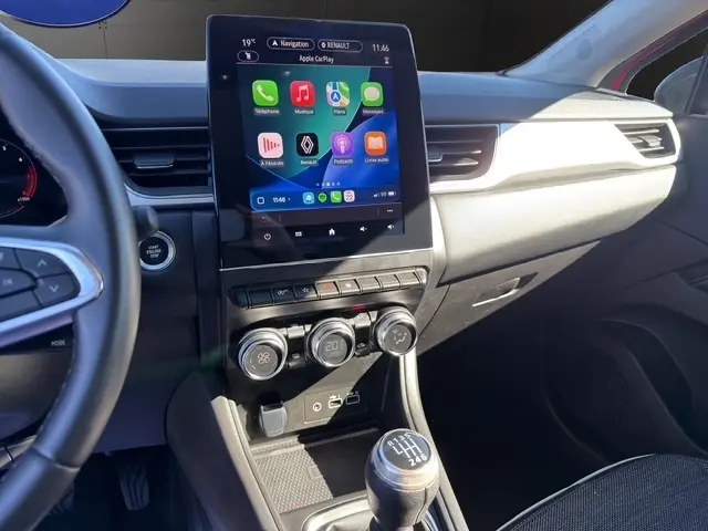 Vue intérieure côté conducteur du tableau de bord du Renault Captur rouge 2024 avec écran tactile 10,4 pouces et boîte manuelle.