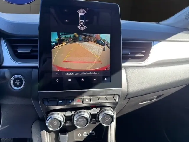 Vue intérieure du tableau de bord du Renault Captur rouge 2024, écran tactile affichant la caméra de recul et commandes climatisation.