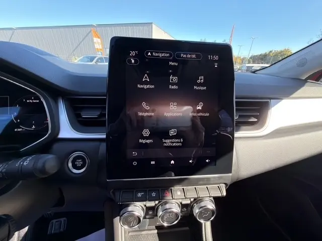 Vue intérieure du tableau de bord du Renault Captur rouge 2024, avec écran tactile central 10,4 pouces et commandes climatisation.