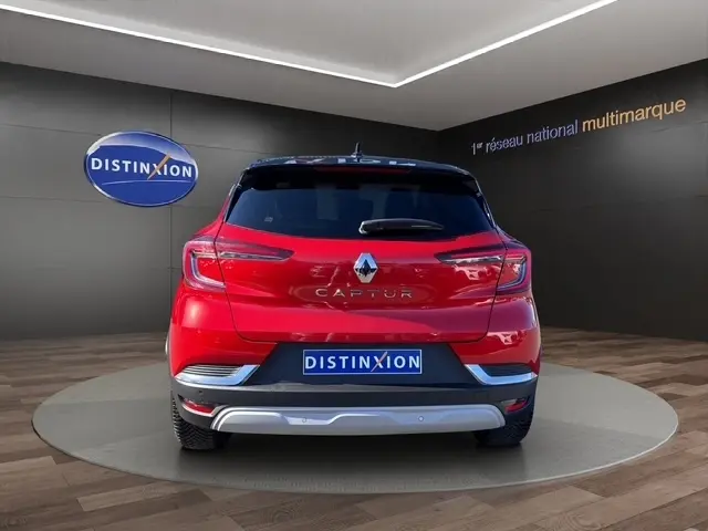 Vue arrière d'un Renault Captur rouge 2024 avec feux LED et logo distinctif sur fond showroom.