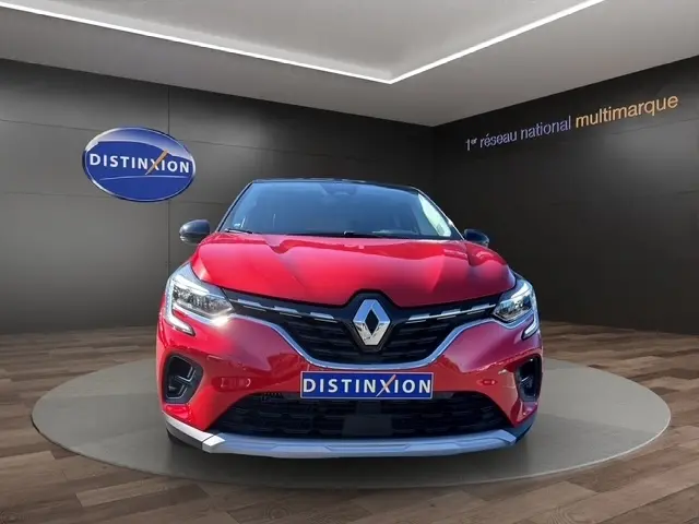 Vue de face du Renault Captur Techno TCe 90 rouge 2024 avec calandre noire et logo chromé, en showroom Distinxion.