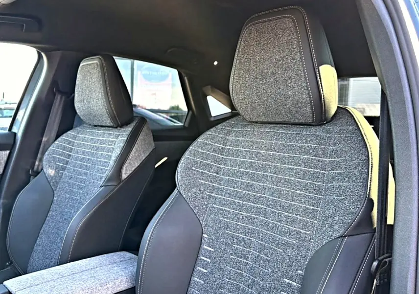 Gros plan sur les sièges avant en tissu gris et cuir noir du Peugeot 3008 1.2 hybrid 145 allure 2025, côté droit ouvert.