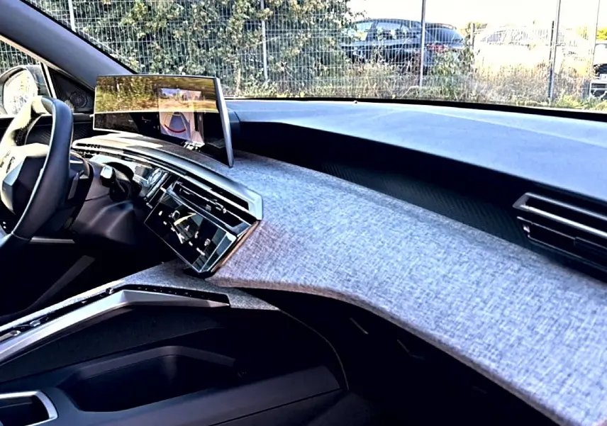 Vue intérieure côté passager du tableau de bord du Peugeot 3008 2025 avec écran tactile et finition tissu gris clair.