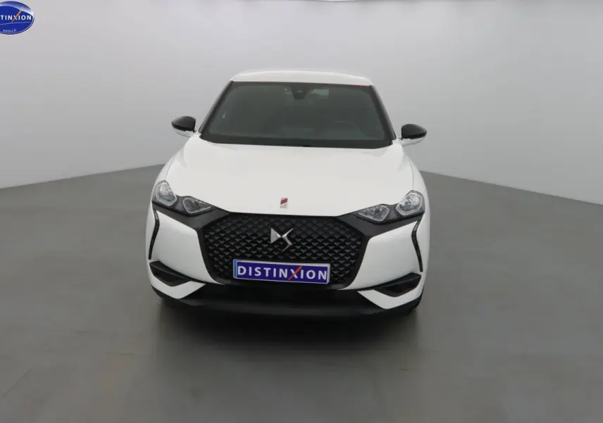 Vue frontale d'une DS3 Crossback blanc banquise avec calandre noire et phares anguleux dans un studio gris.
