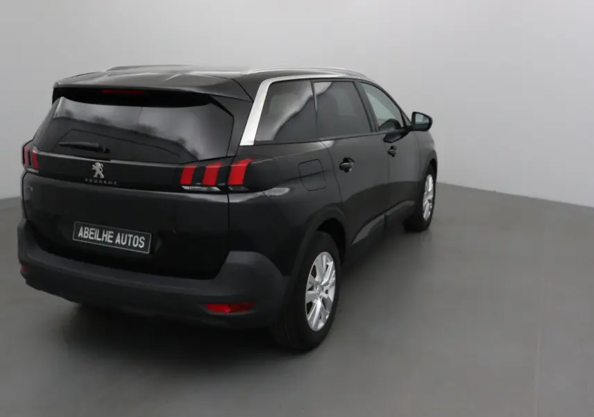 Peugeot 5008 noir en 3/4 arrière droit, avec feux arrière distinctifs et vitres teintées dans un studio.