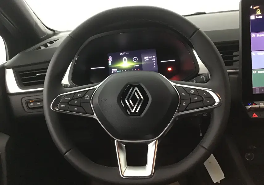 Volant multifonction noir avec logo Renault au centre, tableau de bord numérique et écran tactile latéral du Renault Captur 2025.