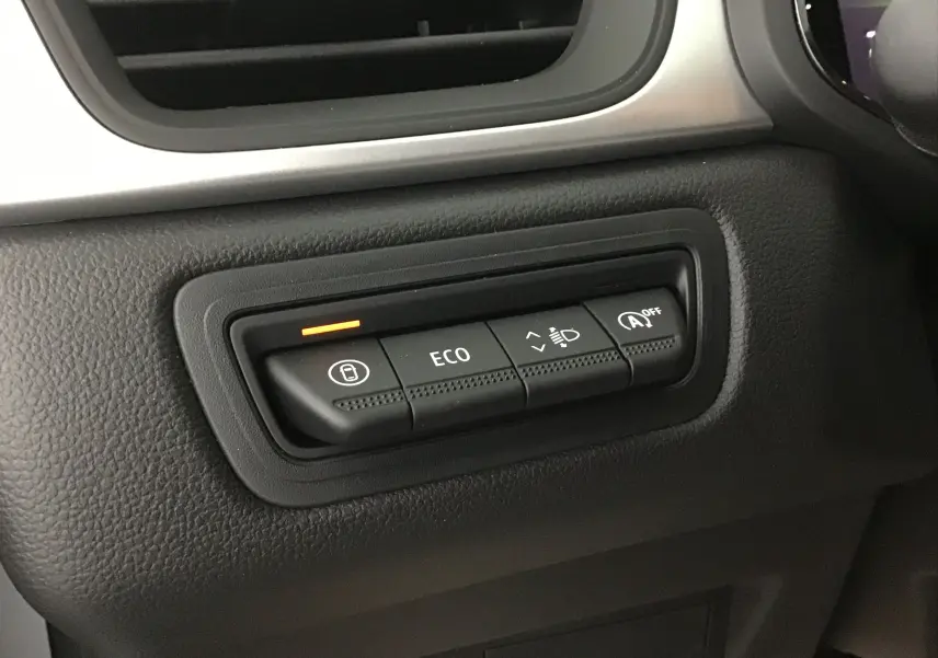 Gros plan sur les boutons de commande noirs du tableau de bord du Renault Captur 2025, avec témoin orange allumé.