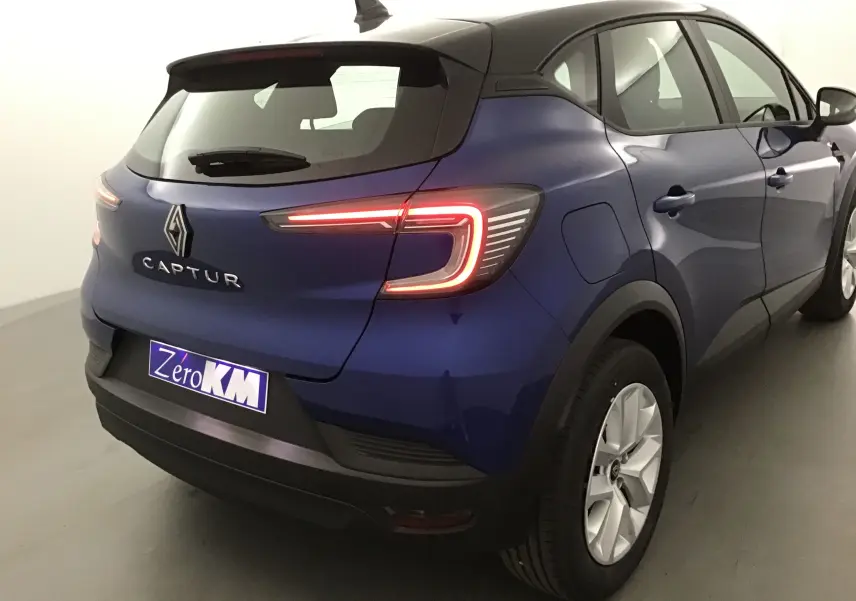 Vue 3/4 arrière droite du Renault Captur 2025 bleu iron et noir avec feux LED allumés dans un studio.