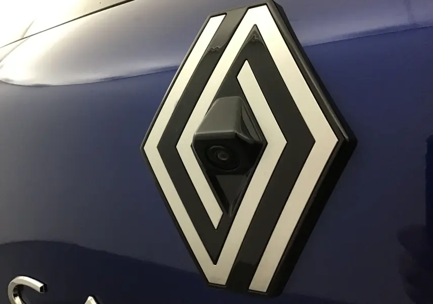 Gros plan sur le logo Renault avec caméra intégrée sur la carrosserie bleu iron du Captur 1.0 TCE 90 Evolution 2025.