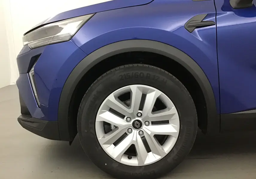Gros plan sur la roue avant gauche d'un Renault Captur 2025 bleu iron avec jante alliage et détails noirs autour.