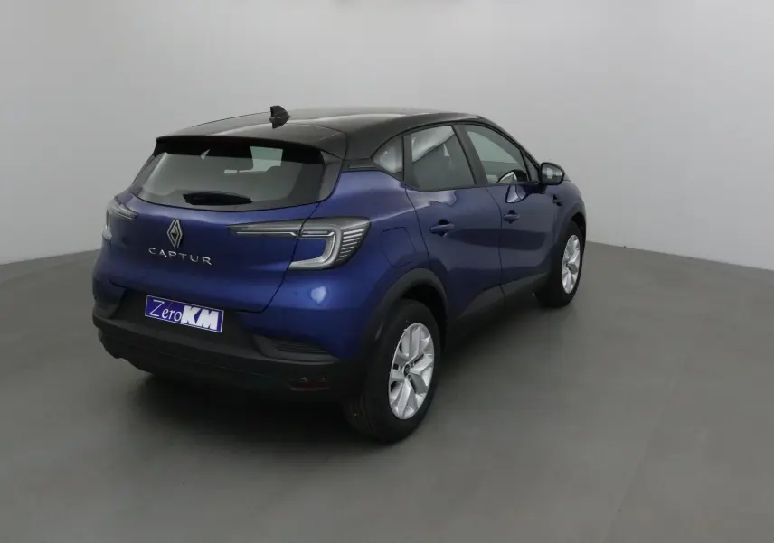 Vue 3/4 arrière droite du Renault Captur 1.0 TCE 90 Evolution bleu iron avec toit noir, en intérieur neutre.