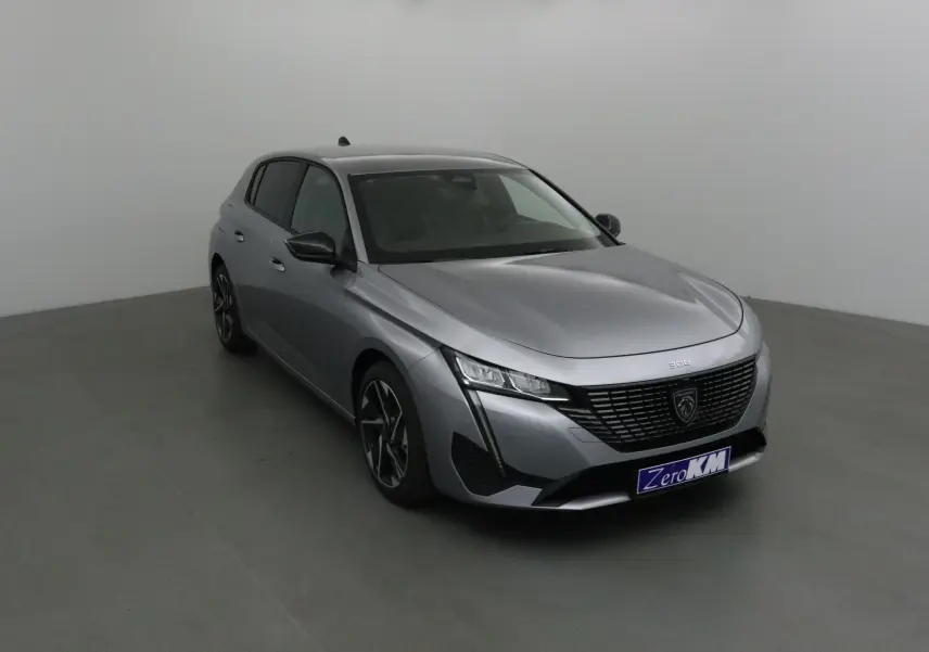 Peugeot 308 gris Artense vue 3/4 avant droit, avec calandre noire et jantes alliage distinctives.