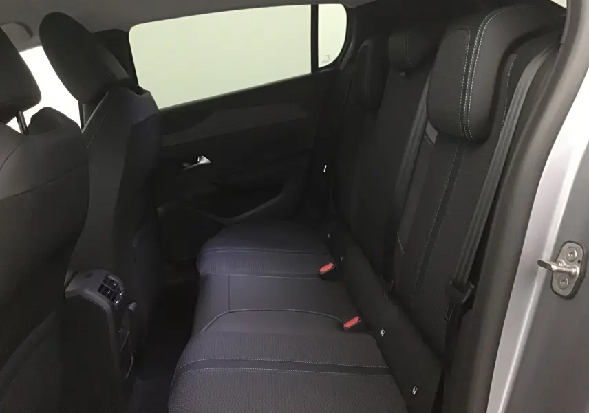 Vue intérieure arrière côté droit de la Peugeot 308 gris Artense, montrant les sièges arrière en tissu noir avec surpiqûres blanches.