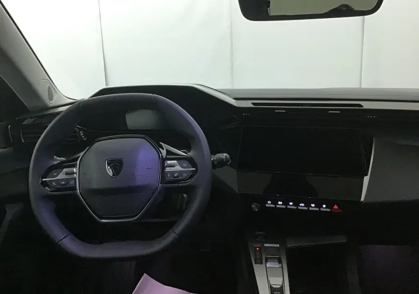 Vue intérieure du poste de conduite de la Peugeot 308 gris Artense, avec volant multifonction et tableau de bord numérique.