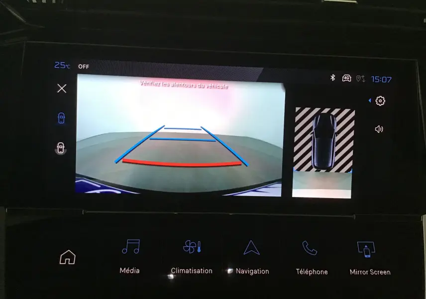 Vue de la caméra de recul affichée sur l'écran multimédia d'une Peugeot 308 gris Artense avec aides au stationnement visibles.