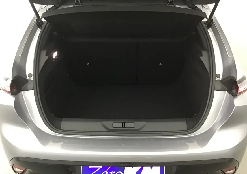 Coffre ouvert vu de l'arrière d'une Peugeot 308 gris Artense, montrant l'espace de chargement vide et l'éclairage intérieur.
