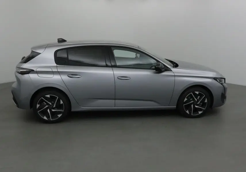 Profil côté droit de la Peugeot 308 gris Artense avec jantes alliage noires et vitres teintées sur fond neutre.