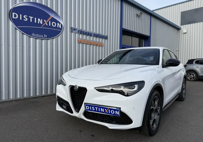 Vue 3/4 avant droite de l'Alfa Romeo Stelvio blanc Alfa 2023 avec calandre caractéristique et phares LED distinctifs.