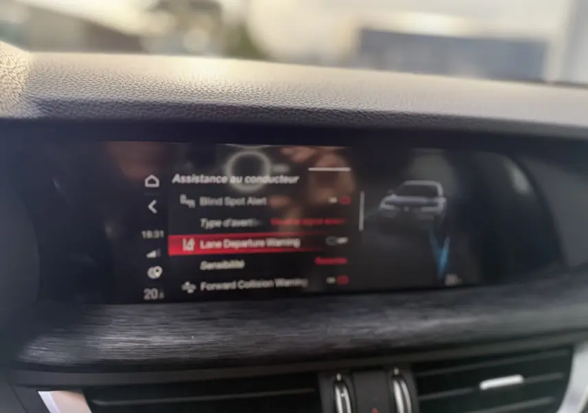 Écran central de l'Alfa Romeo Stelvio 2023 affichant les options d'assistance au conducteur avec interface moderne et finition bois.