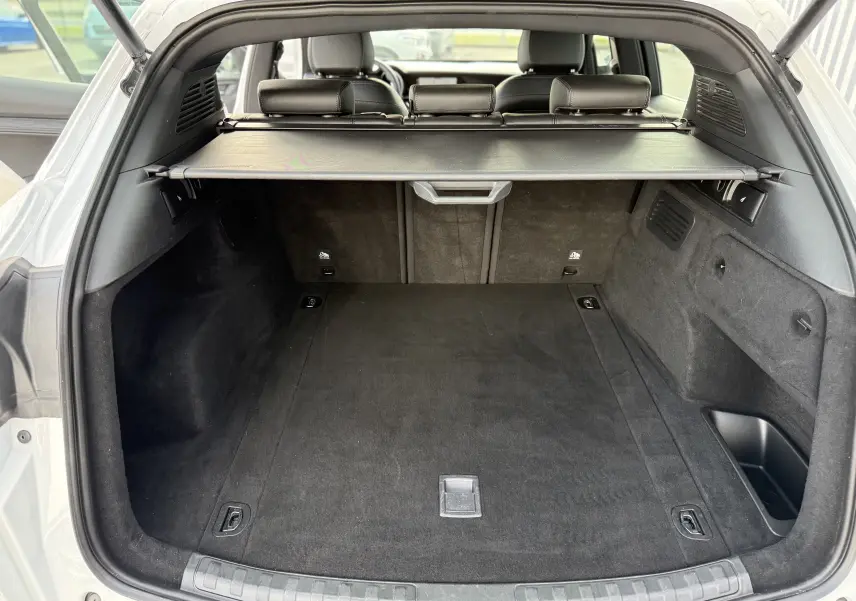 Coffre ouvert d'un Alfa Romeo Stelvio blanc Alfa 2023, vue arrière montrant l'espace de chargement avec cache-bagages noir.
