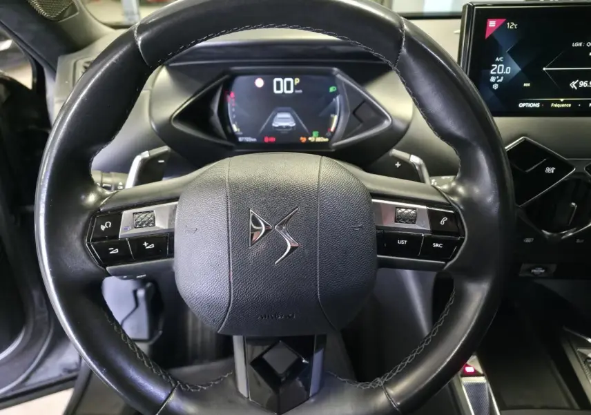 Vue rapprochée du volant en cuir noir du DS3 Crossback 2022 avec tableau de bord numérique et écran tactile central.