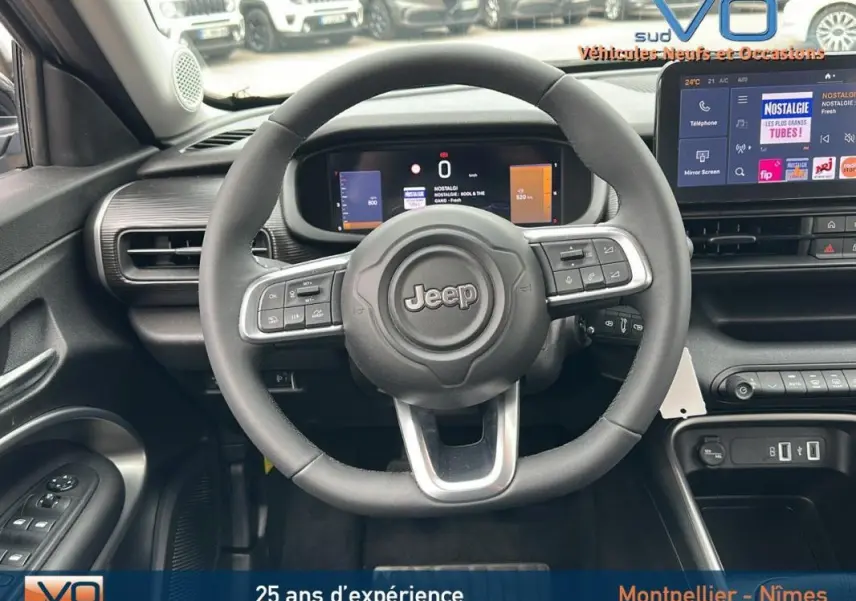 Vue intérieure du volant Jeep Avenger 2024 gris foncé, avec tableau de bord numérique et écran tactile central.