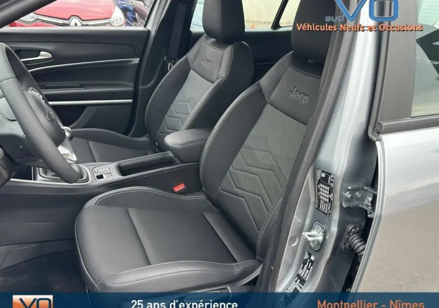 Intérieur du Jeep Avenger gris foncé, vue côté gauche sur les sièges avant en tissu et cuir avec logo Jeep brodé.