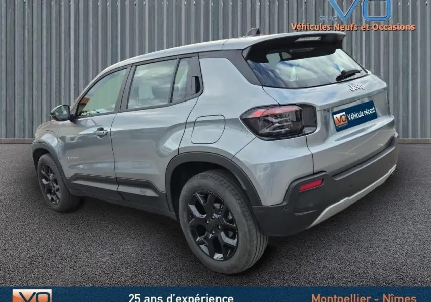 Jeep Avenger gris foncé vue 3/4 arrière côté gauche, avec jantes noires et toit noir contrastant.